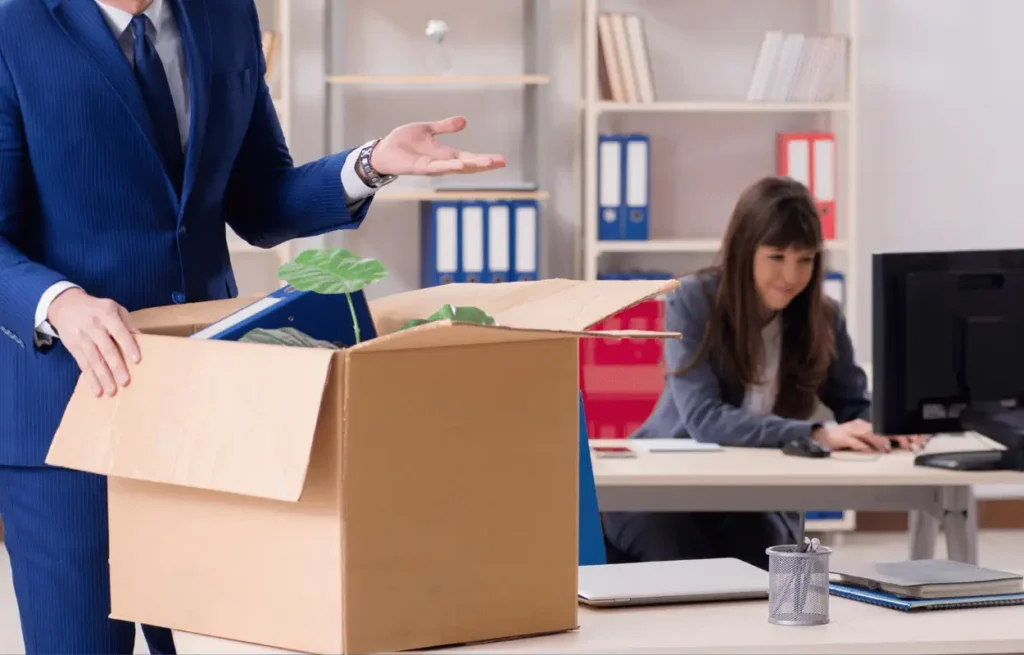 Image of a woman packing her things, possibly being fired for suing for sexual harassment.