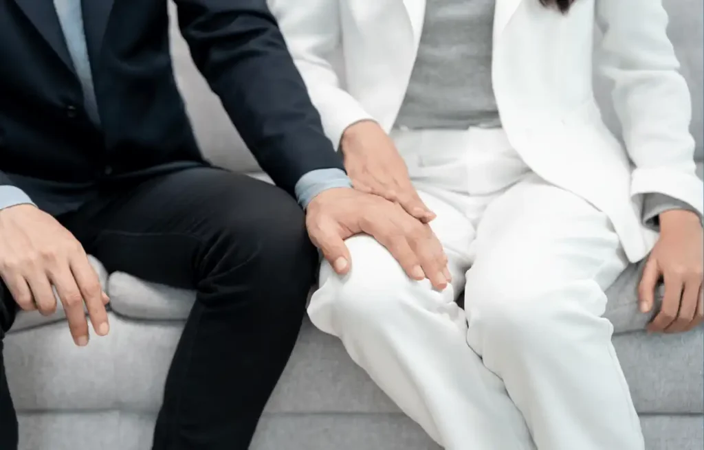 Image of a man with his hand on the leg of a female employee potentially sexually harassing her.