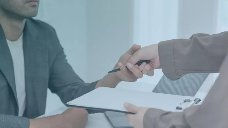 A man reaches out to grab employee’s hand as she is handing him a pen, showing sexual harassment by her boss in Oregon.