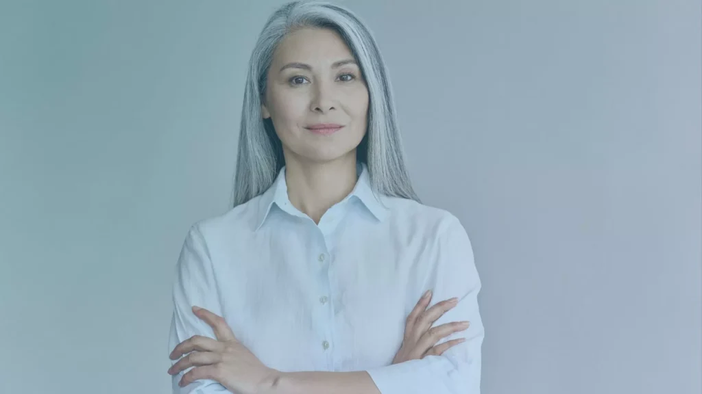 An older lady is crossing her arms and smiling, after winning a case about age discrimination from her Oregon employment.