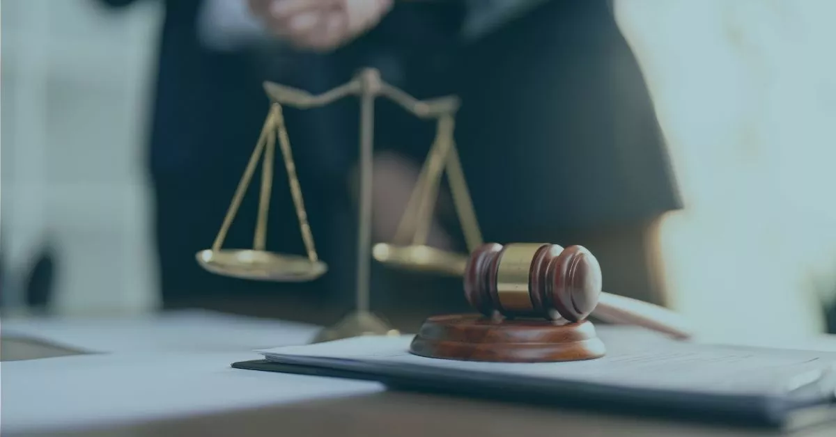 An older man stands out of focus behind a gavel and scale in a law office, as he is dealing with a case about age discrimination in Oregon from his employment.