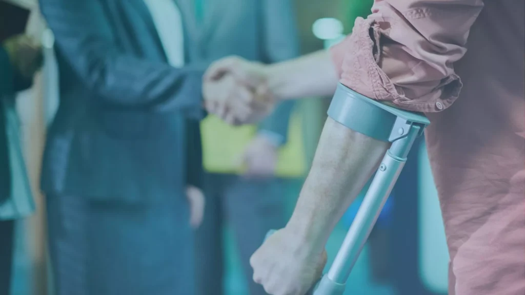 Injured worker using crutches while meeting with an attorney after a unfair dismissal after an injury at work.