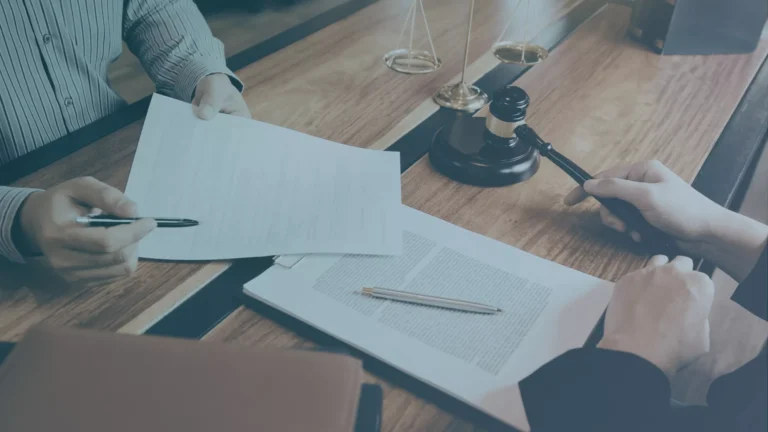Hands reviewing a constructive discharge lawsuit paperwork at a table with a judge&rsquo;s gavel and scales of justice nearby.