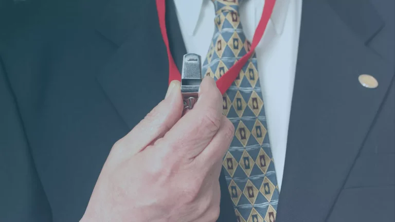 Close-up of a person in a suit holding a whistle on a red lanyard, symbolizing whistleblowing in the workplace.