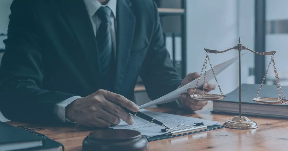 Attorney reviewing paperwork at a desk with a pen, legal scales, and gavel in the foreground.