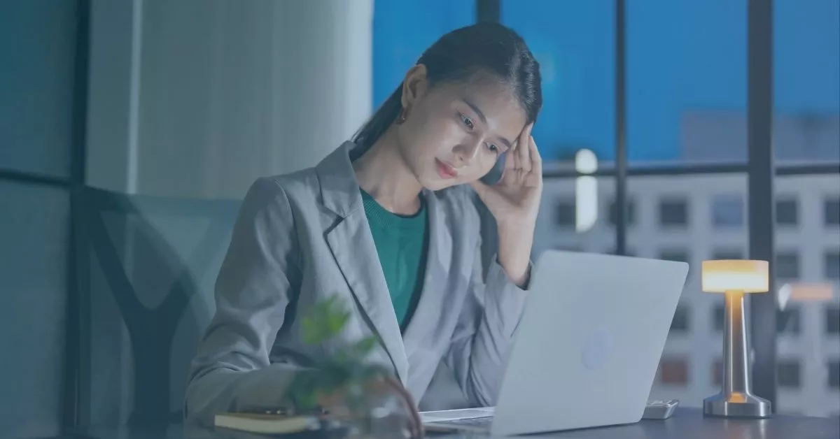 Woman working late on a laptop looking stressed, representing overtime issues and salaried employee rights in Oregon.