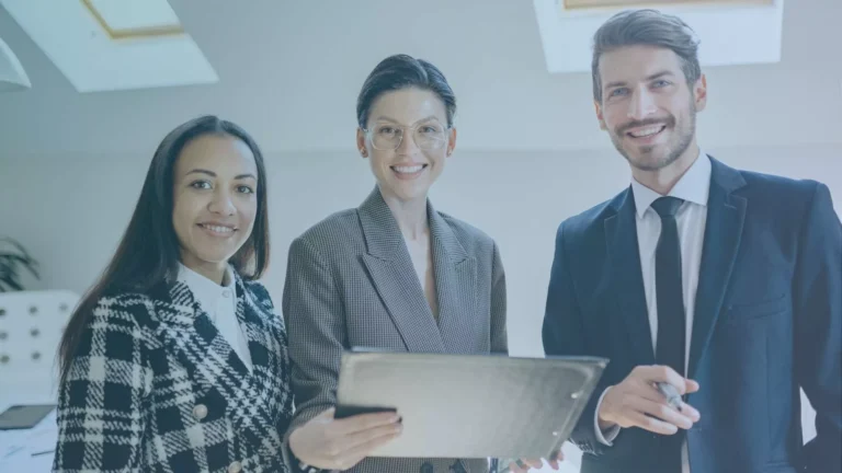 Three business professionals smiling and holding a tablet in an office, symbolizing salaried employee rights in Oregon.