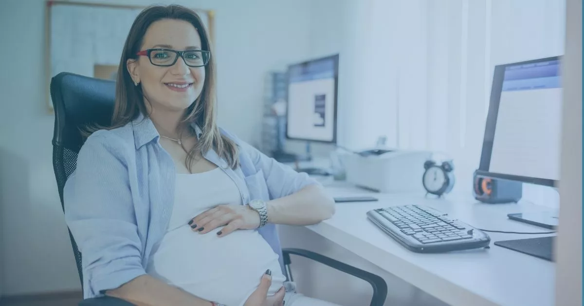 Pregnant employee sitting at a desk in an office, representing maternity leave rights and workplace protections for expecting workers.
