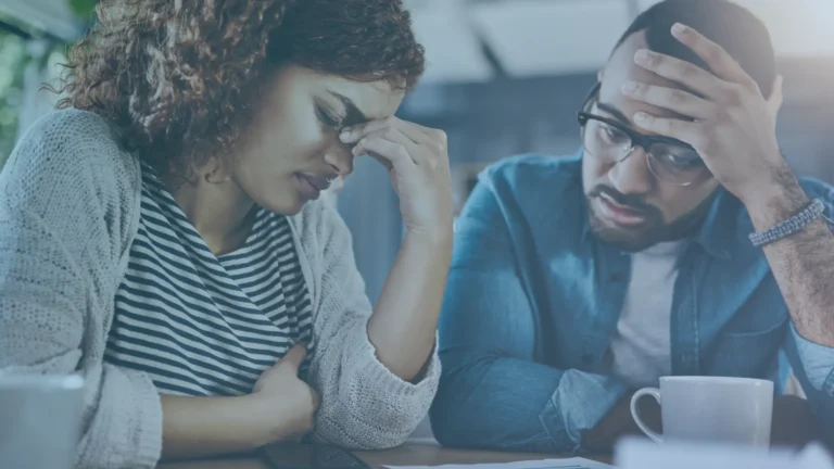 Stressed employees reviewing financial paperwork and household bills after losing a job, illustrating the emotional and financial impact of wrongful termination.