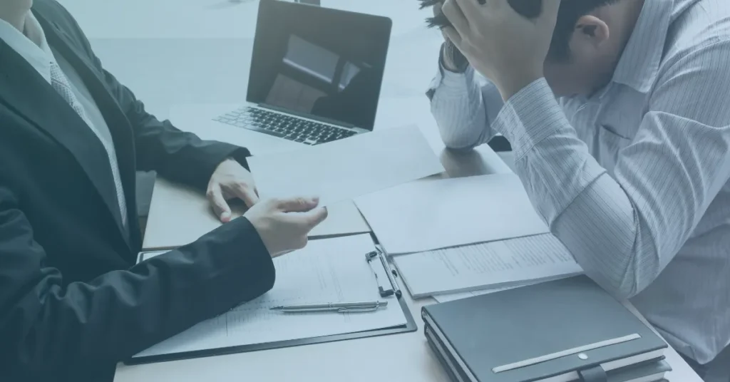 Recently terminated employee meeting with an attorney while reviewing employment documents, legal paperwork, and evidence during an initial wrongful termination consultation.