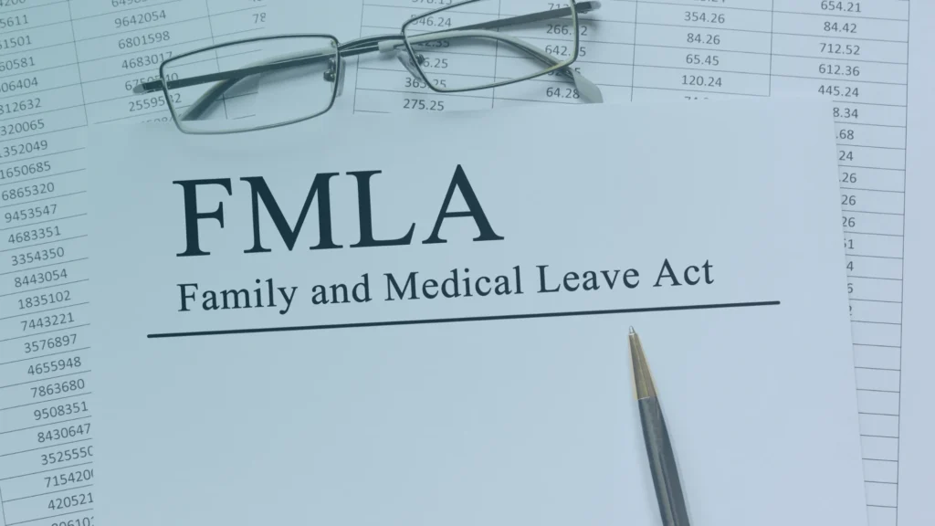 FMLA Family and Medical Leave Act document with eyeglasses and a pen, representing employee medical leave rights and workplace discrimination protections.