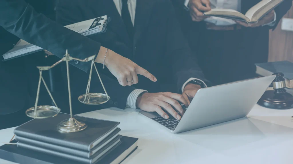 Oregon employment lawyers reviewing wage and overtime records on a laptop with legal books, documents, and scales of justice.